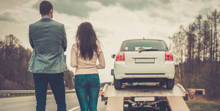Couple near tow-truck picking up broken car